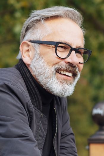 Man with a gray beard smiling outdoors
