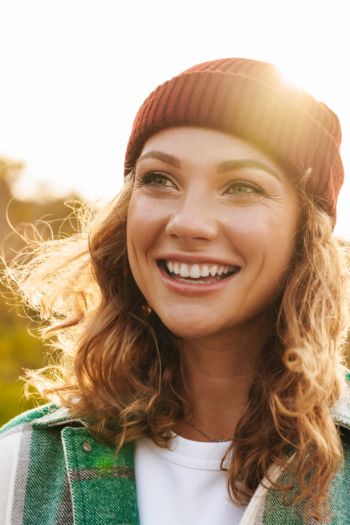 Young woman in a red beanie smiling in the sunlight